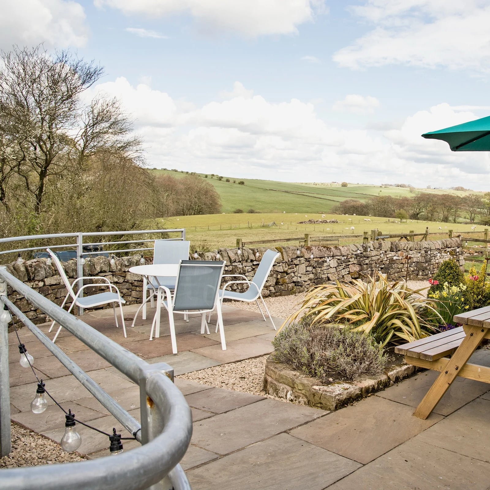 The terrace at dusk, string lights and open fields beyond