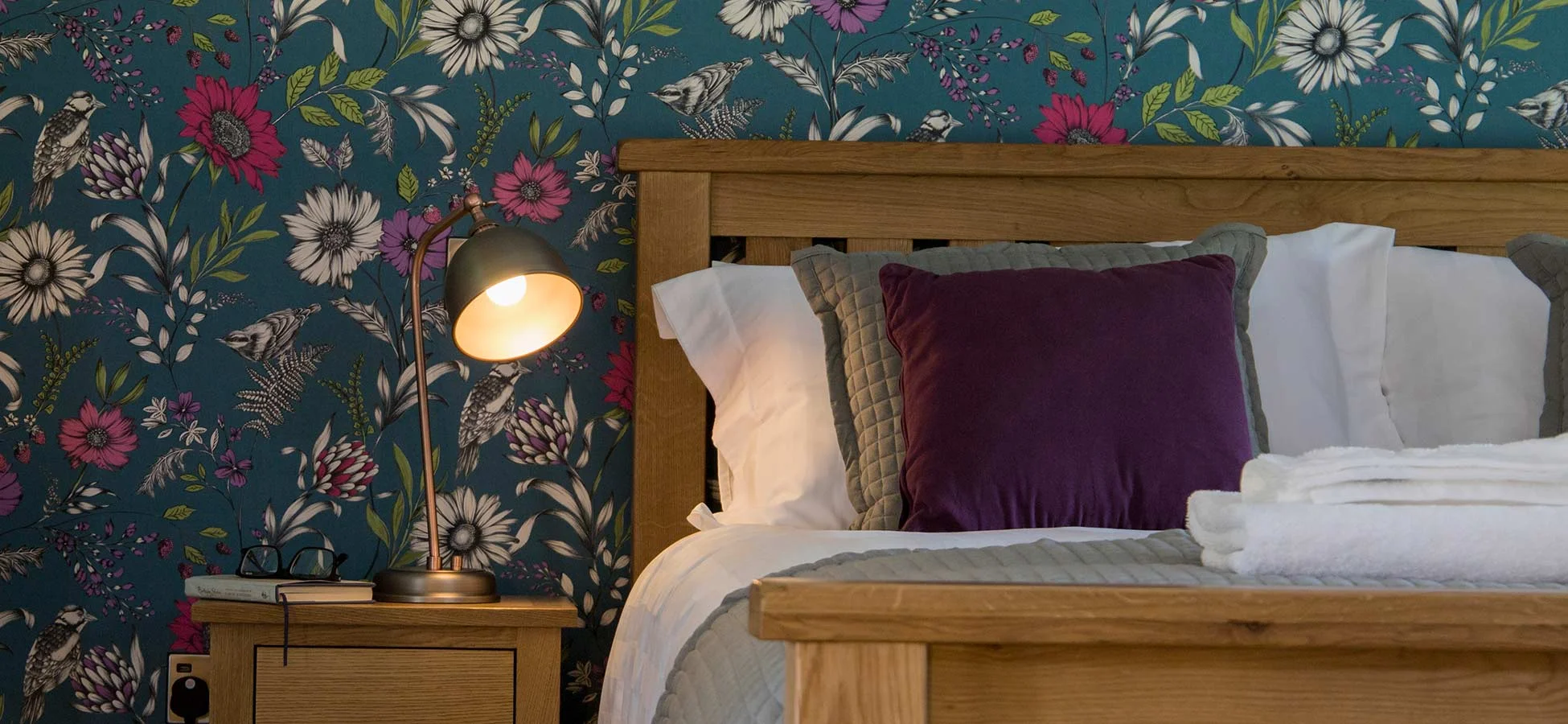The bedroom at Mixon View, with statement wallpaper and original stone